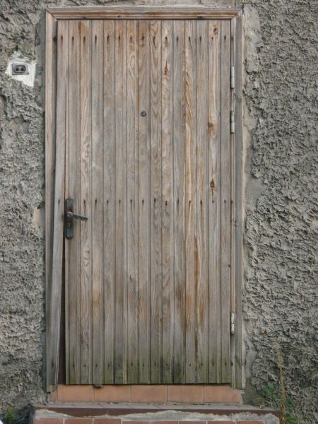 Wooden door in grey tone with worn surface and vertical line pattern.